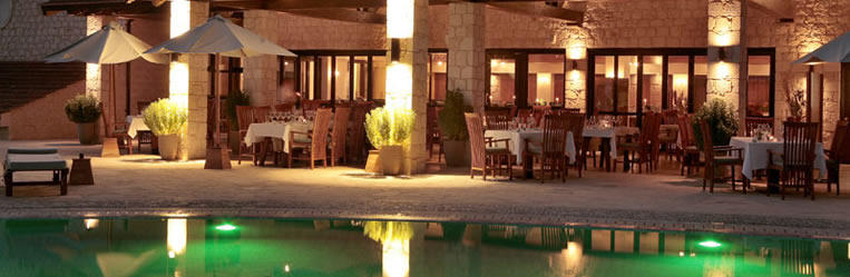 „Amaroula“ – главный ресторан отеля с видом на бассейн – подает блюда региональной и интернациональной кухни. Завтрак сервируется в виде шведского стола. Полупансион предполагает ужин из блюд на выбор по меню или в виде шведского стола. К услугам гостей также изысканный а-ля-карте ресторан „Kamari“ и стильный бар „The Old Bar“, который располагается в бывшем престольном зале с камином, и винный погреб с большим выбором вин собственного производства.